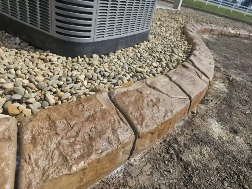 Natural stone style decorative concrete curbing around river rock landscaping