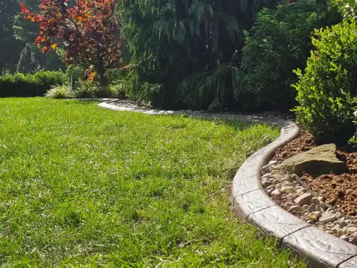 Smooth concrete landscape curbing edging a mulched flower bed