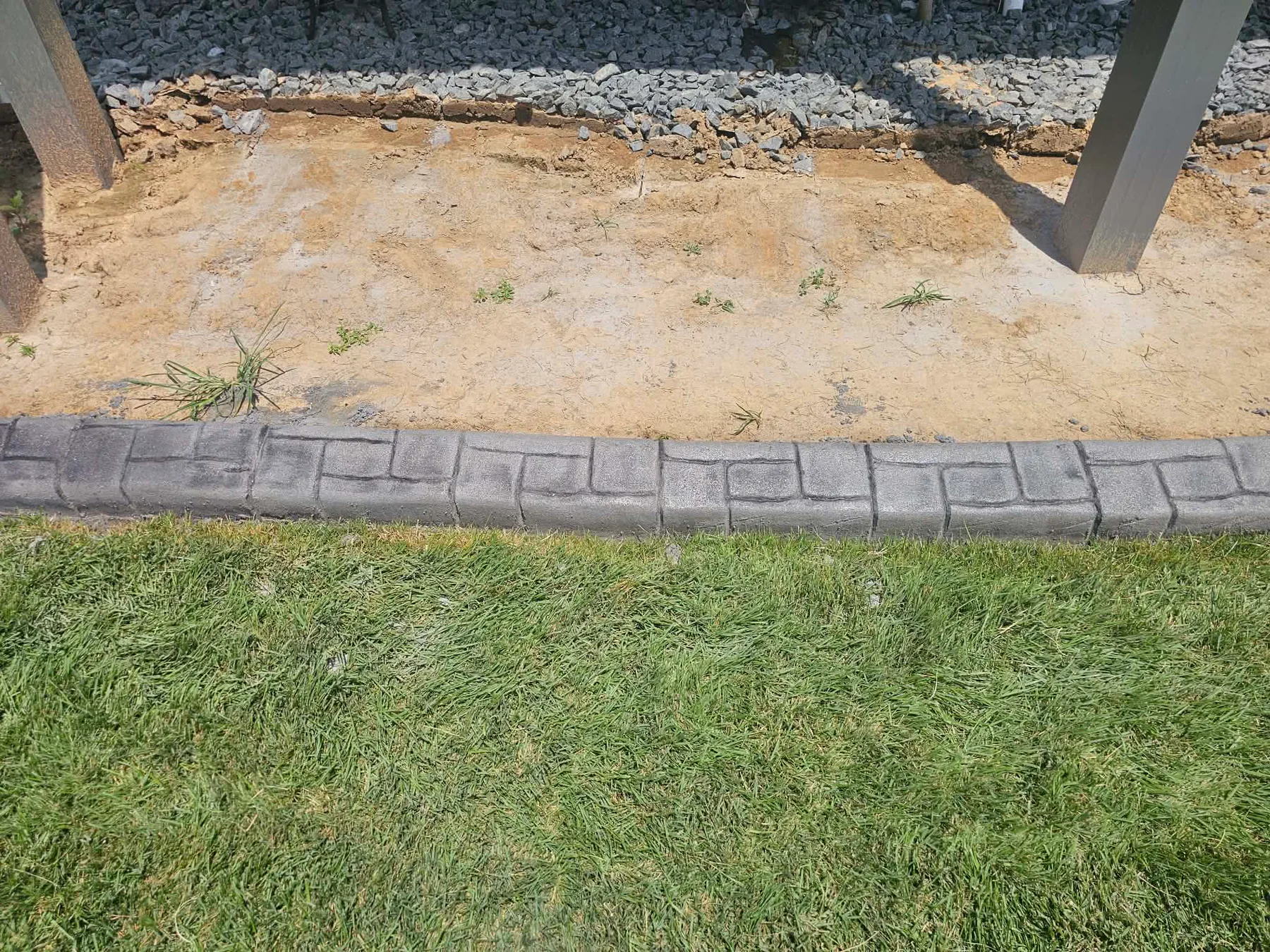 Narrow brick-look concrete border beside a porch