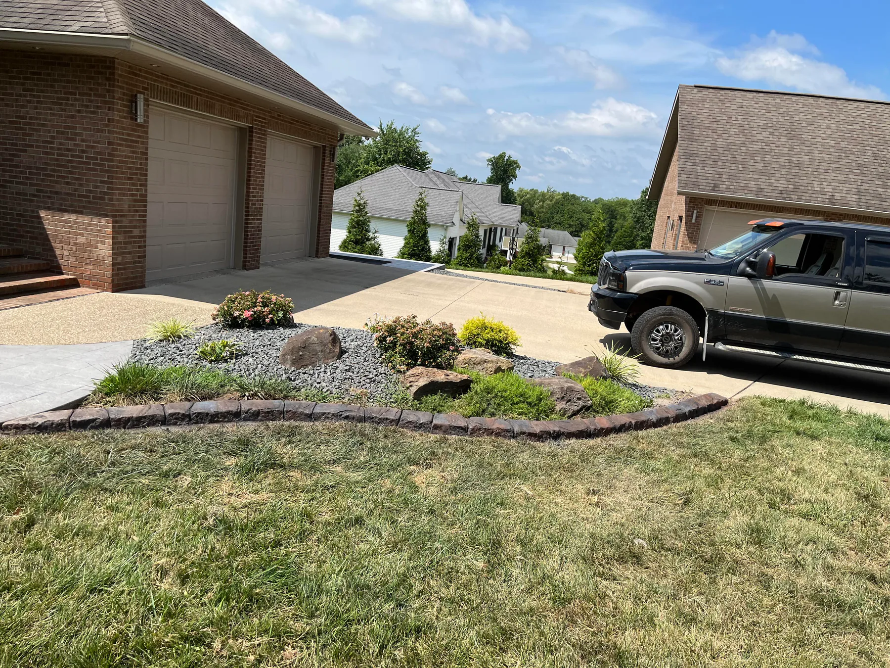 Finished stone-look concrete curbing beside a driveway