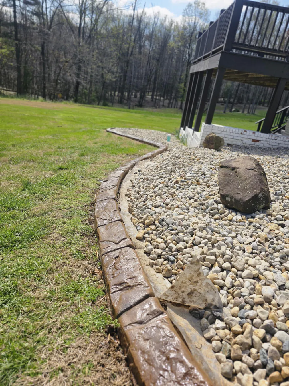 Textured concrete curbing around a mature evergreen bed