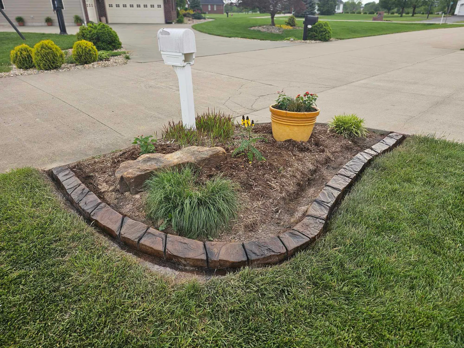 Low-profile decorative curb around a driveway planting bed