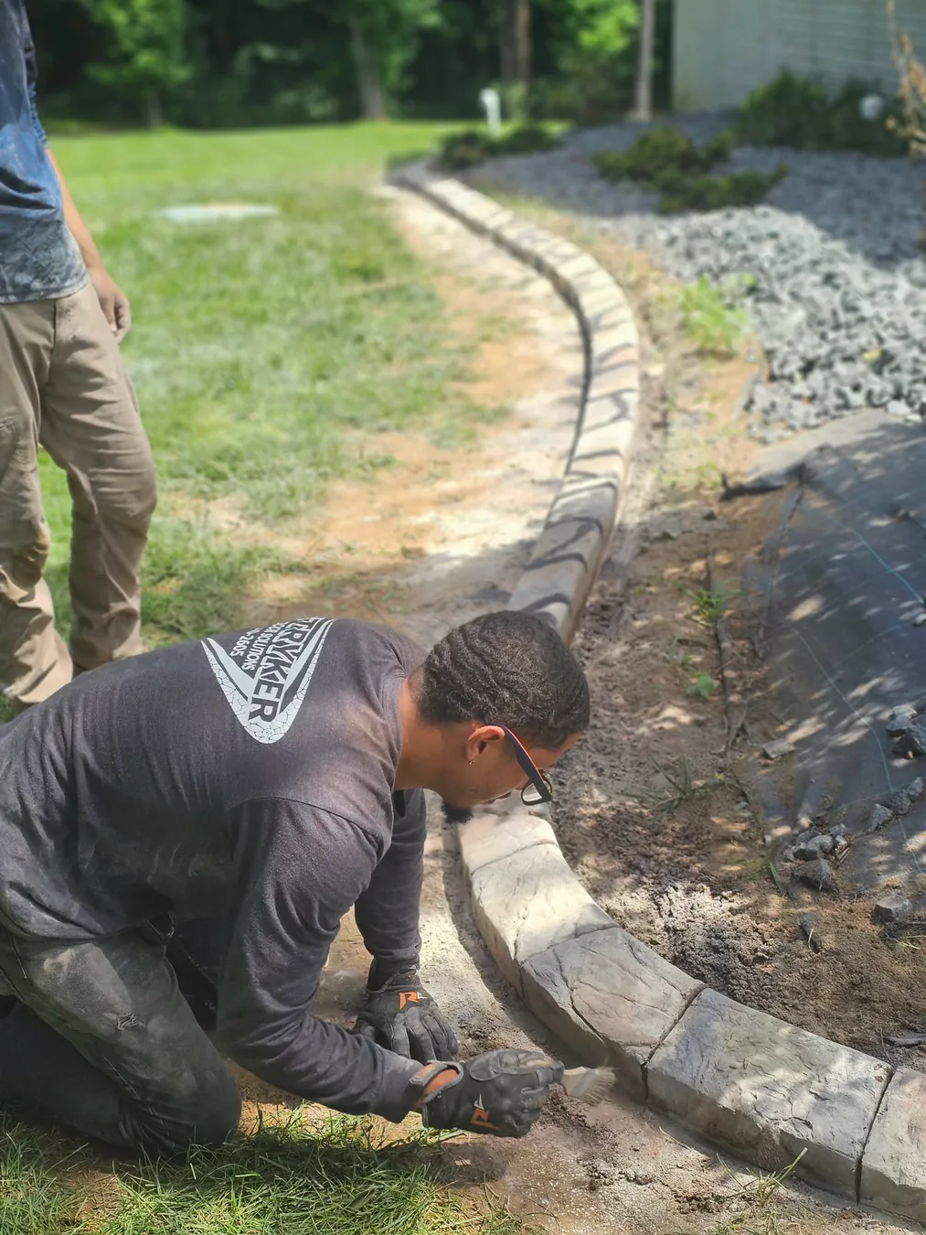 Stryker installer shaping a curved concrete landscape edge