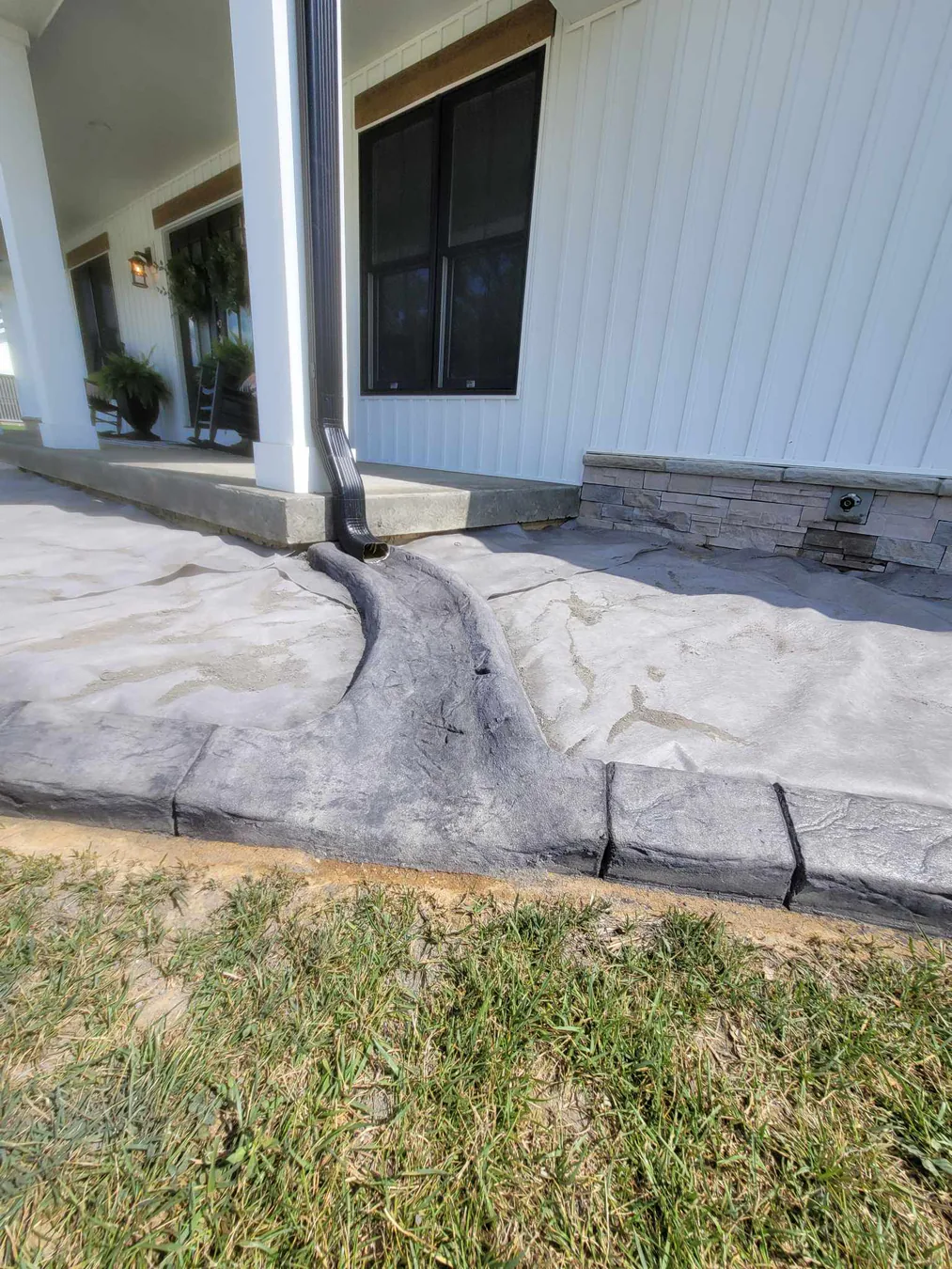 Stamped patio border with a handcrafted downspout transition