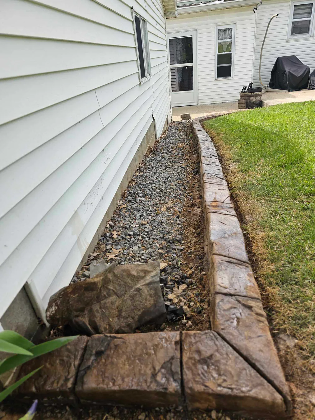 Curved concrete edging around a stone-covered side-yard bed