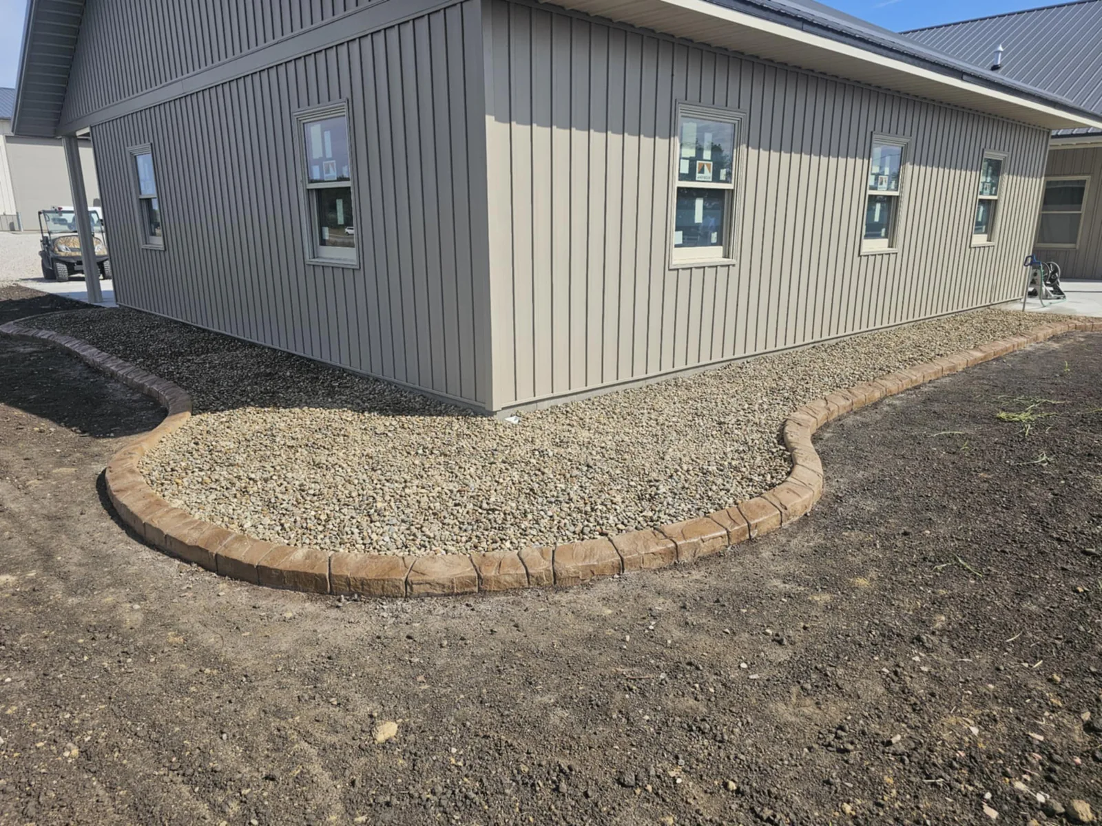 Concrete curbing defining a rock landscape bed around a commercial building