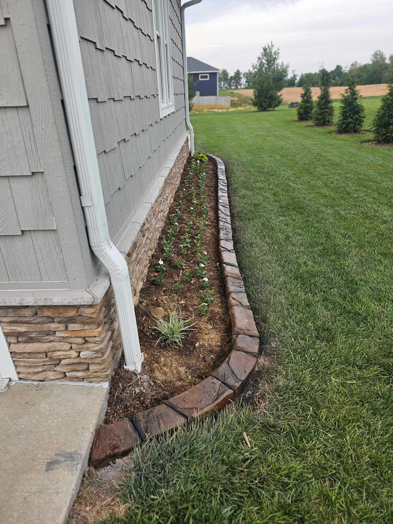 decorative concrete curbing along a maintained flower bed beside a Southern Indiana home