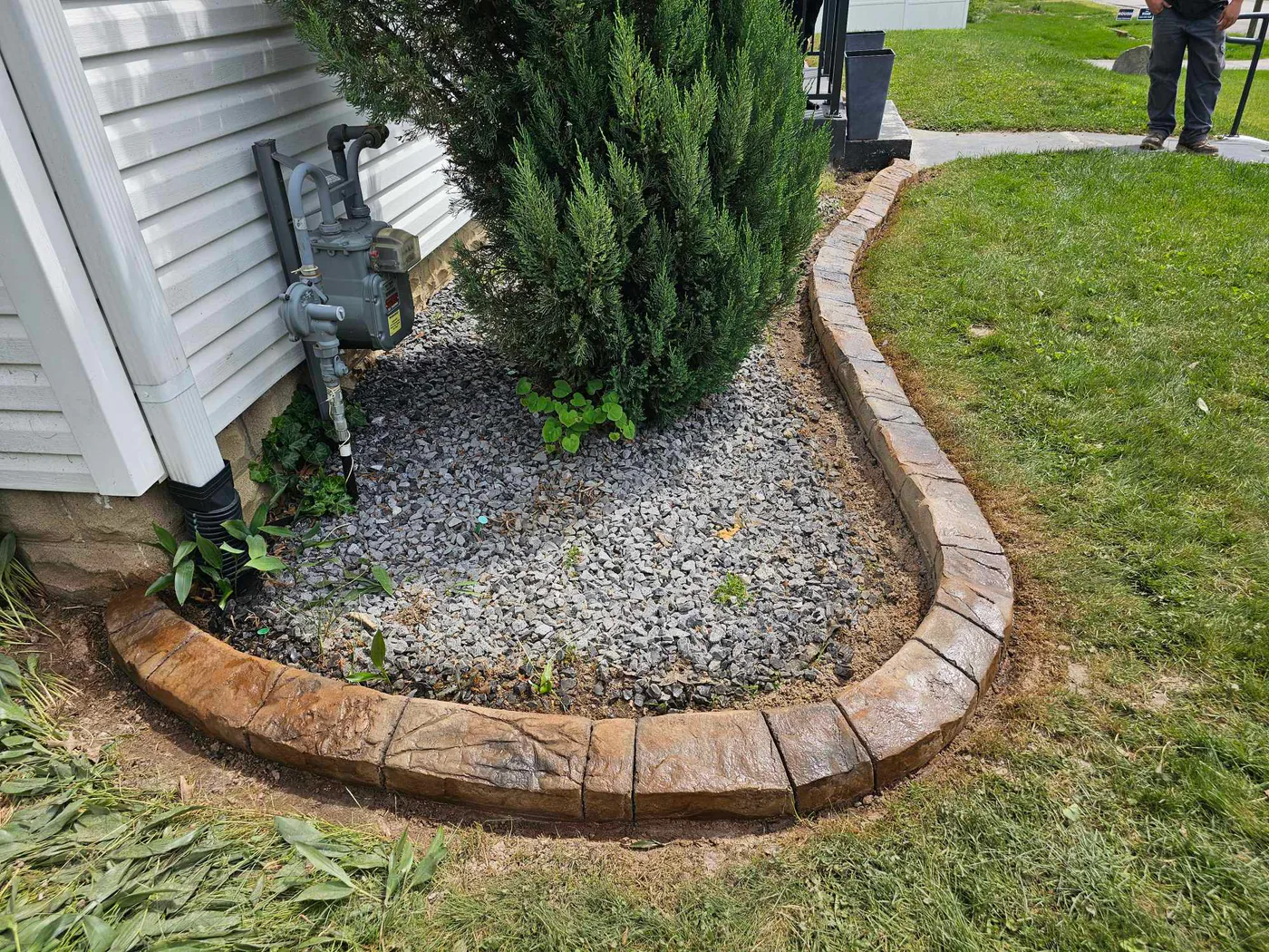 decorative concrete curbing installed around a stone landscape bed beside a Southern Indiana home