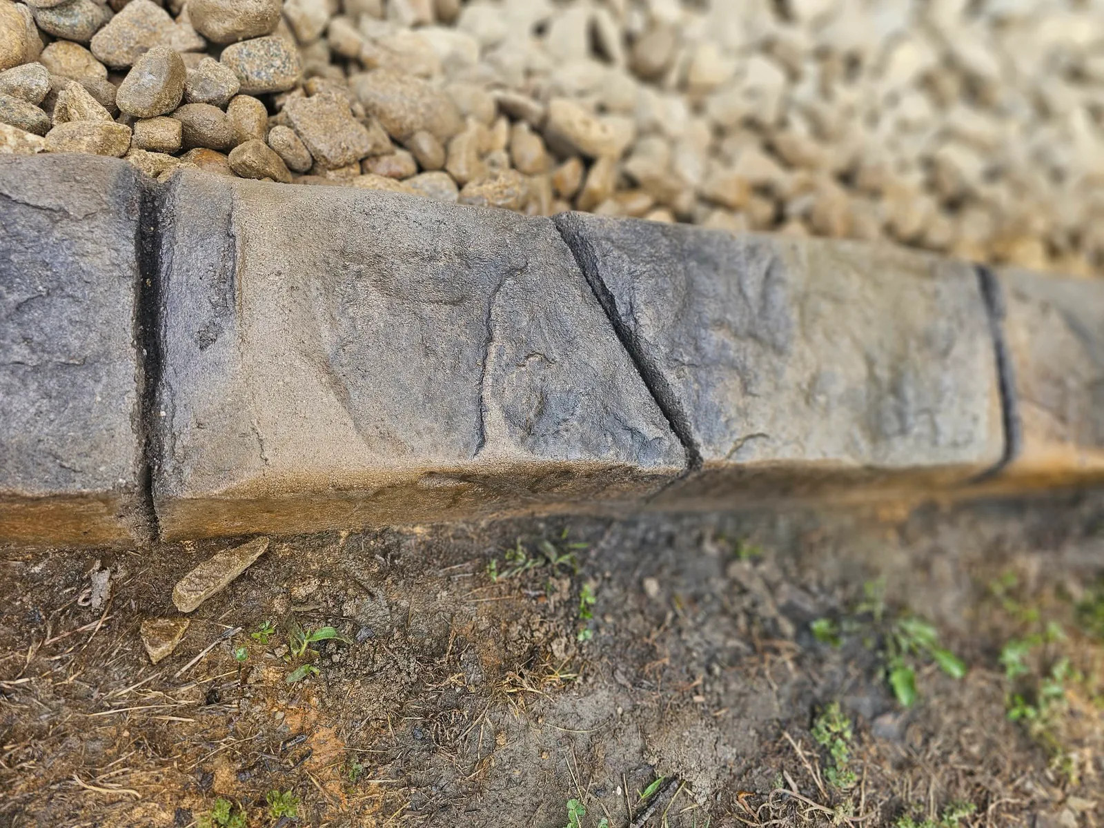 Close view of freshly resealed decorative concrete curbing beside landscape stone