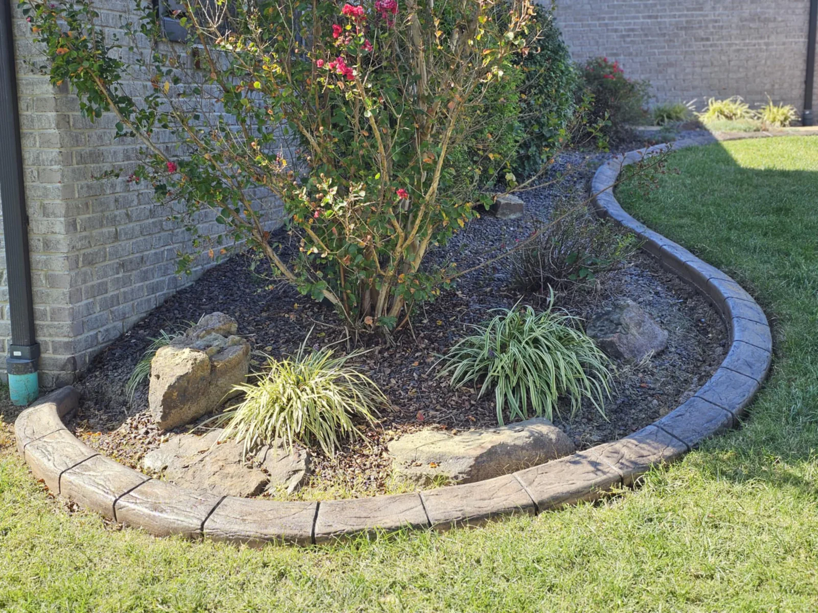Decorative natural-stone-style concrete border around a landscaped garden bed