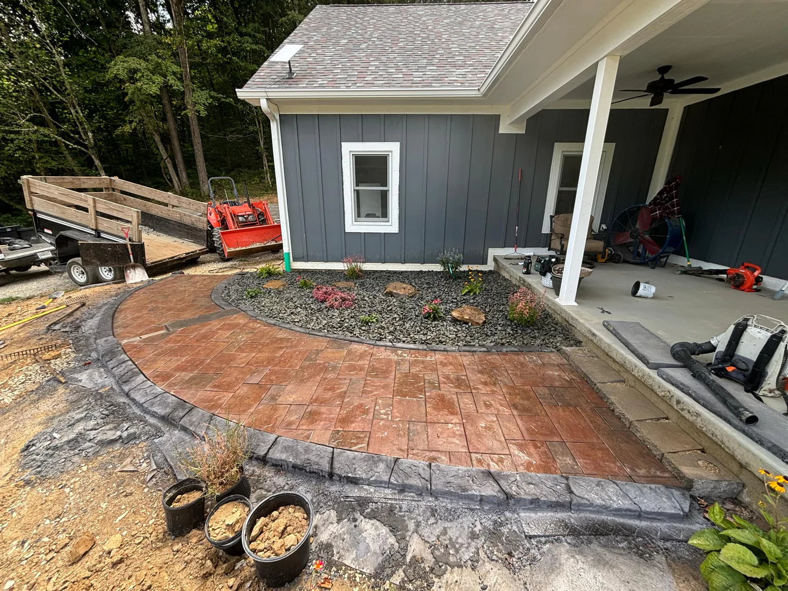 Stamped concrete hardscape installation in progress beside a covered patio