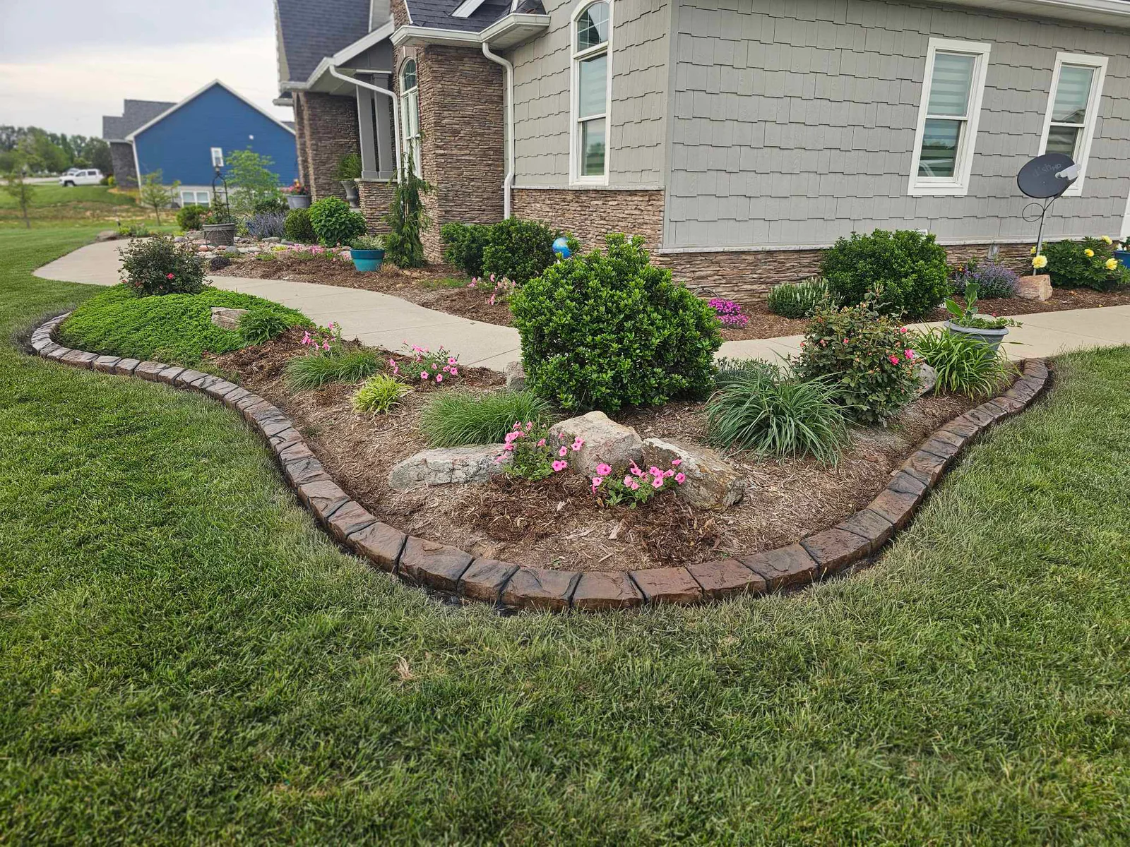 Finished residential landscape installation with planted beds and decorative edging