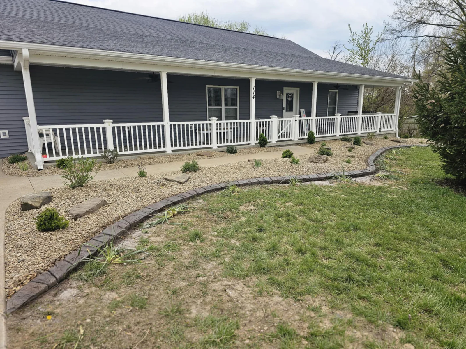 New rock landscape installation with planted shrubs and concrete edging