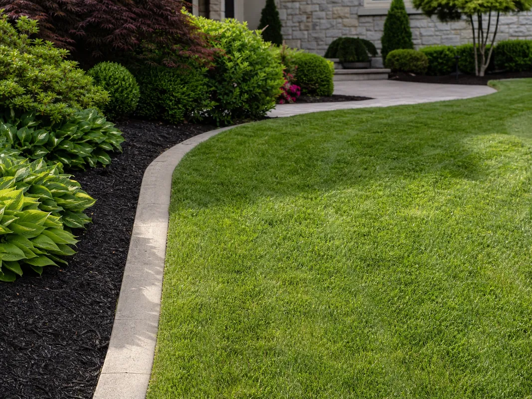 Lawn maintenance process in Washington IN showing mowing and trimming around landscape borders.