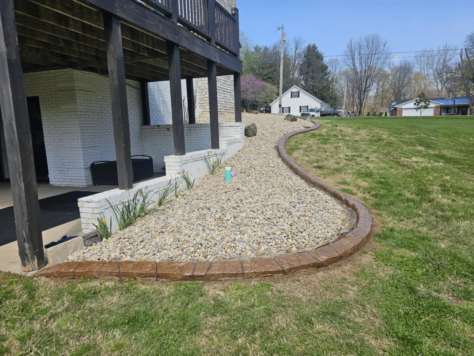 Natural-stone-style concrete curbing around a large river-rock landscape bed
