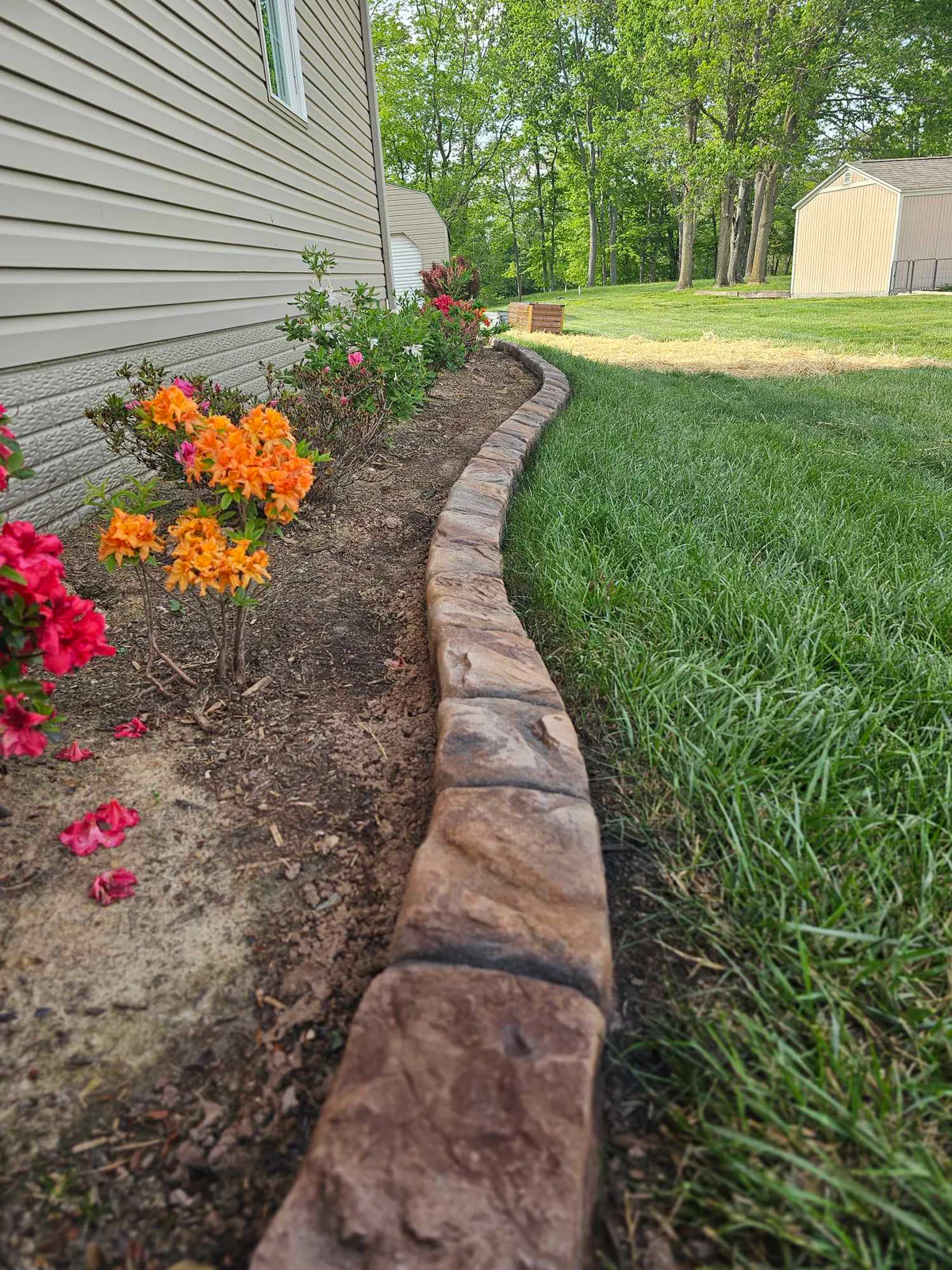 Natural-stone-style concrete curbing along a flowering foundation bed