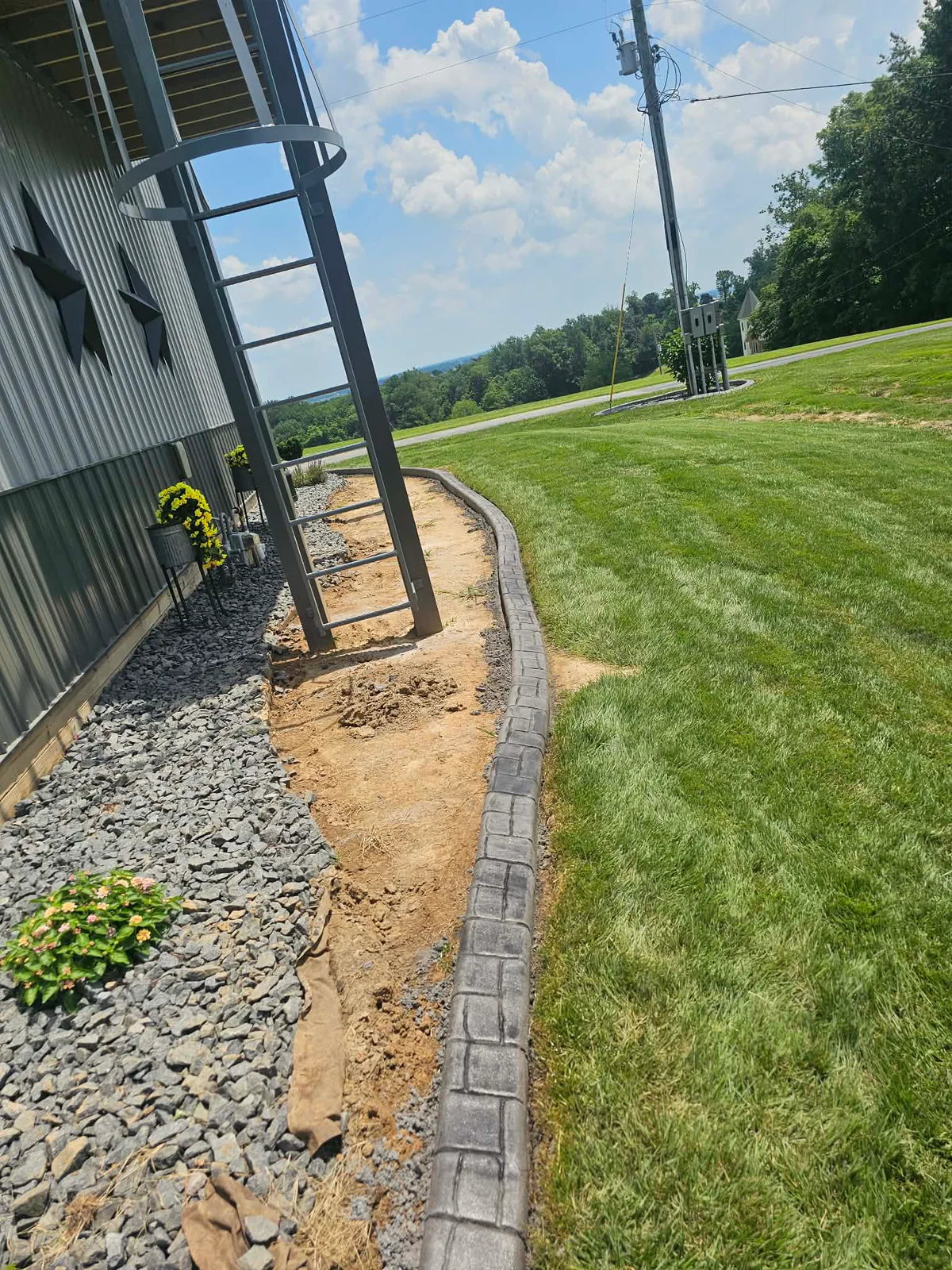 Freshly installed stamped concrete curb following a commercial landscape bed
