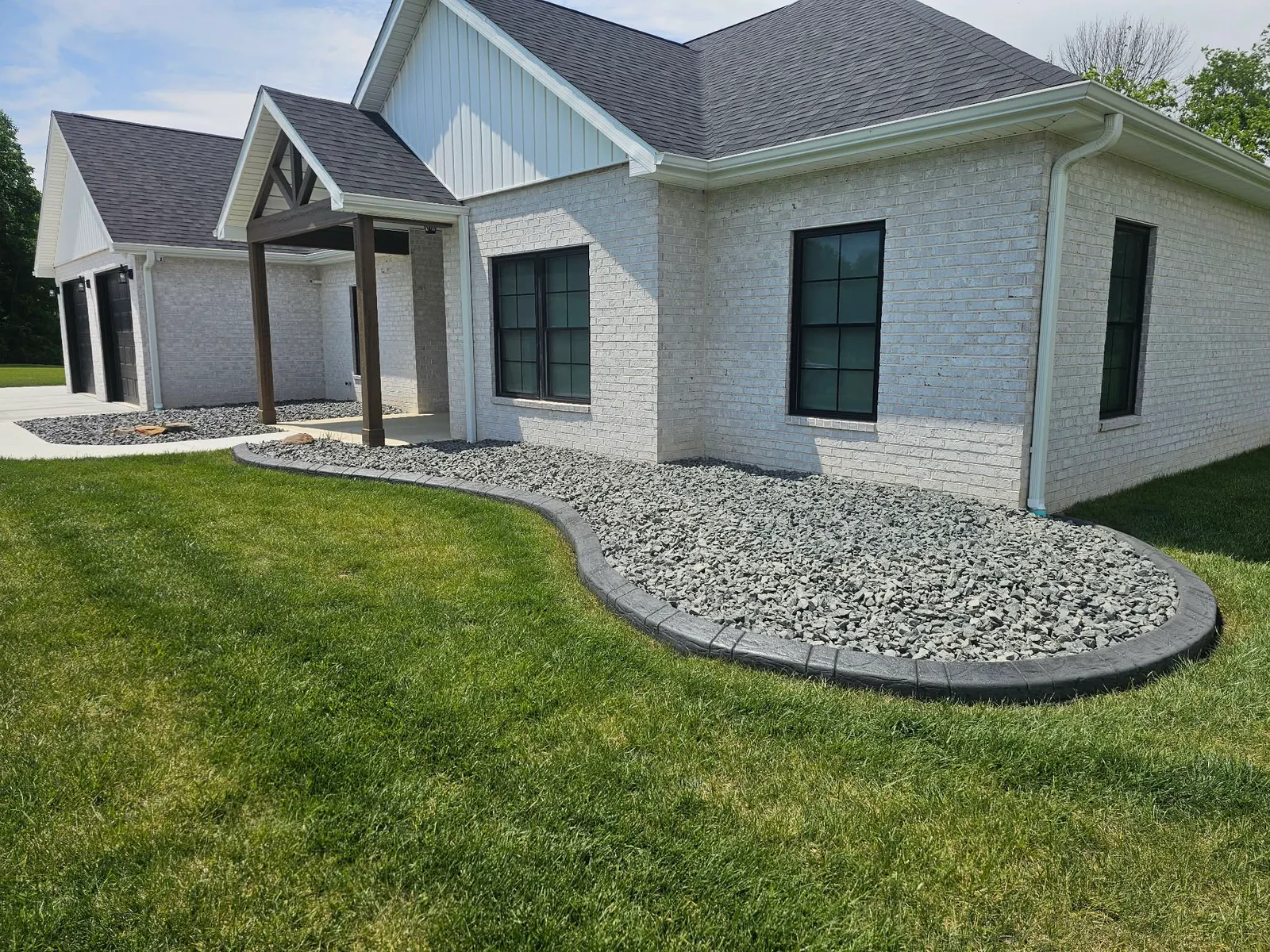 Gray stamped concrete curbing around a rock landscape bed at a home